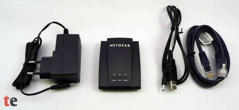 Netgear WNCE2001 Adapter samt Zubehör: Netzteil, USB-Stromversorgungskabel und Ethernet-Netzwerkkabel.